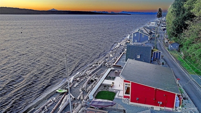 aerial view at dusk featuring a water view