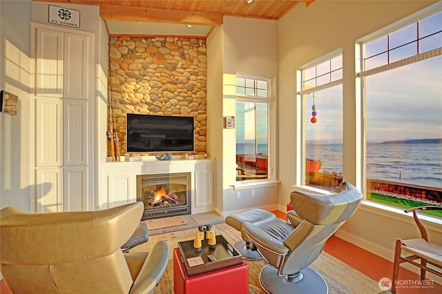 living room with wood ceiling, a glass covered fireplace, baseboards, and beamed ceiling