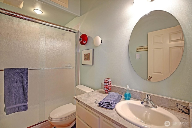 full bath featuring toilet, vanity, and a stall shower
