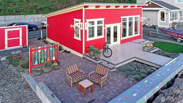 exterior space with a wooden deck, an outbuilding, and french doors