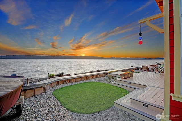 dock area with a lawn and a deck with water view
