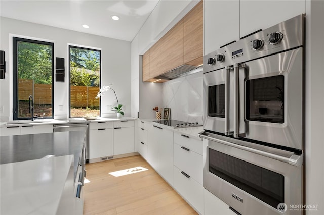 17720 SE 63rd Pl, Bellevue, WA 98006 - kitchen featuring modern cabinets, appliances with stainless steel finishes, light countertops, light wood-style flooring, and recessed lighting