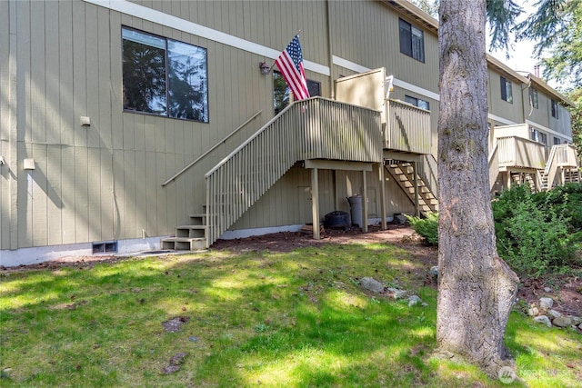 back of property with a lawn, a deck, and stairway