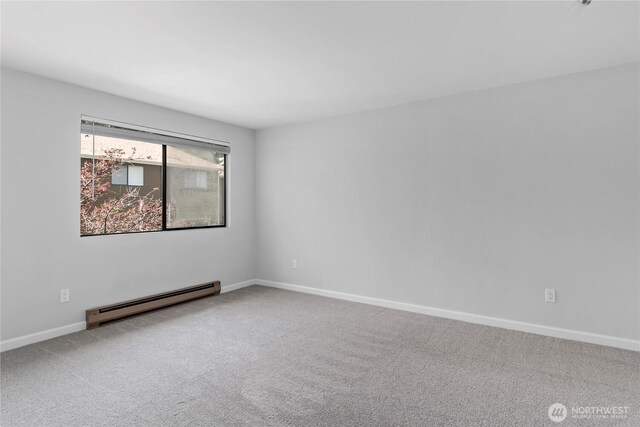 unfurnished room with a baseboard heating unit, baseboards, and carpet flooring