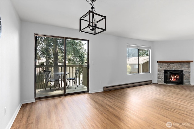 unfurnished living room featuring a stone fireplace, an inviting chandelier, baseboards, a baseboard radiator, and wood finished floors