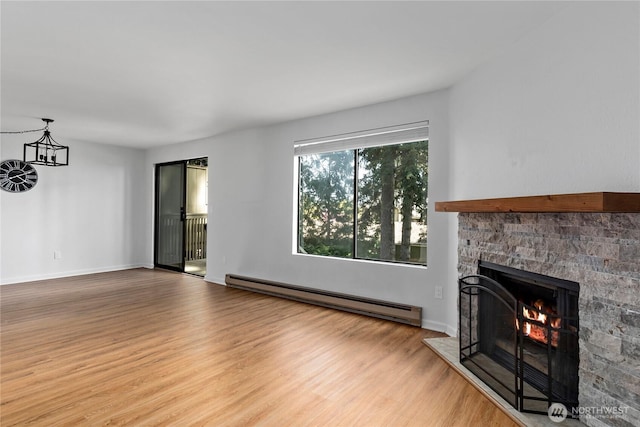 unfurnished living room featuring a stone fireplace, a baseboard heating unit, baseboards, and wood finished floors