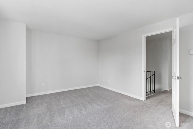carpeted empty room featuring baseboards