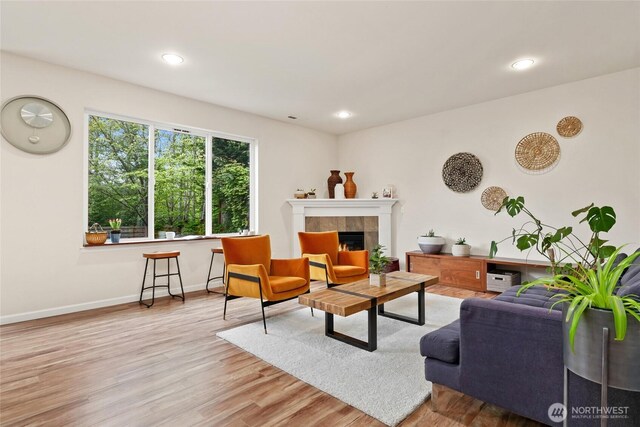 living area featuring a tiled fireplace, recessed lighting, baseboards, and wood finished floors