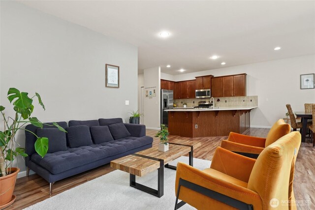 living area featuring baseboards, recessed lighting, and light wood-style flooring
