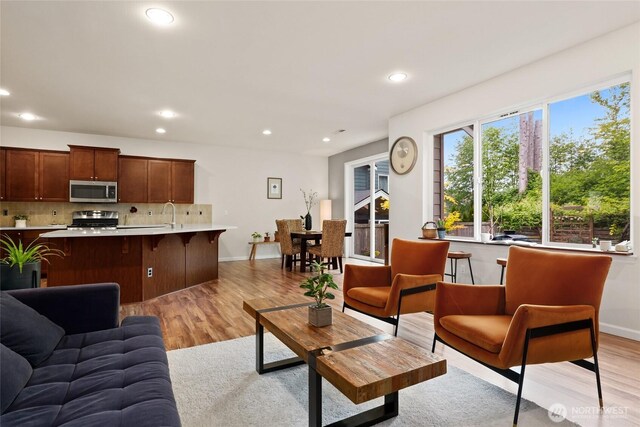 living room with light wood-style floors, baseboards, and recessed lighting