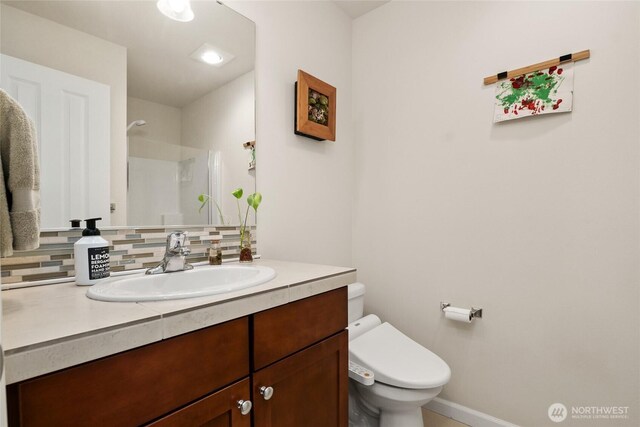 full bath with tasteful backsplash, vanity, toilet, baseboards, and a shower