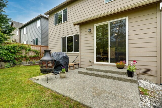back of property featuring fence, a patio, and a lawn