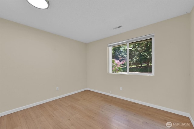 spare room featuring visible vents, light wood-type flooring, and baseboards