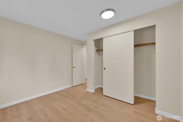 unfurnished bedroom with light wood-style floors, a closet, and baseboards