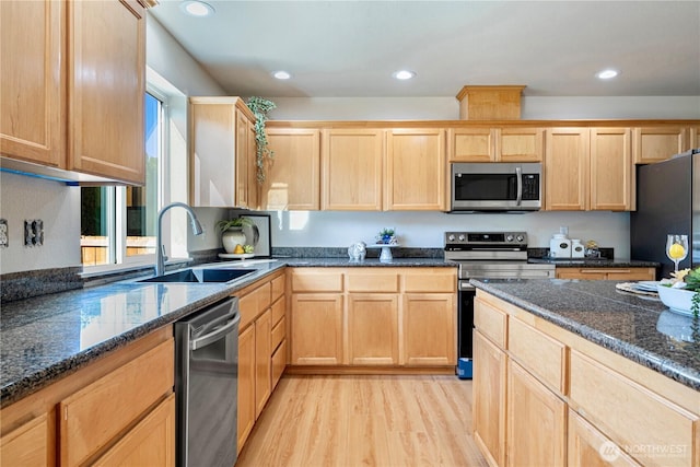 kitchen with light wood-style floors, appliances with stainless steel finishes, light brown cabinets, and a sink