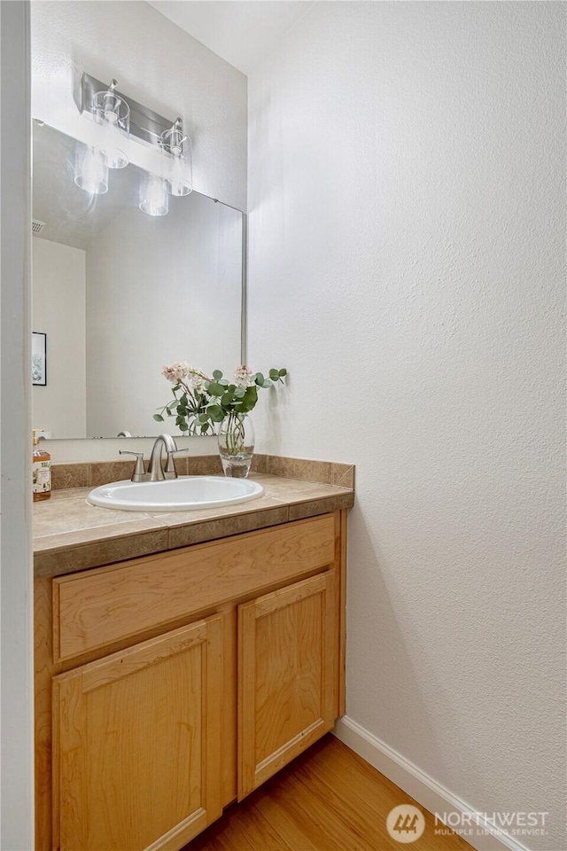 bathroom featuring baseboards, vanity, and wood finished floors