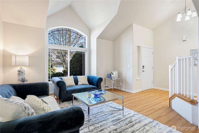 living room featuring high vaulted ceiling, wood finished floors, baseboards, and a notable chandelier