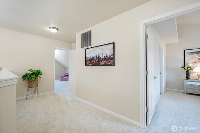 hallway featuring light colored carpet, baseboards, and visible vents