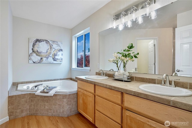 full bath featuring a bath, wood finished floors, a sink, and double vanity