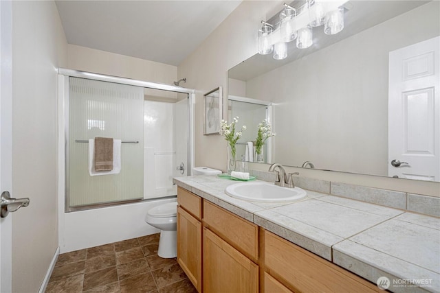 bathroom featuring combined bath / shower with glass door, vanity, and toilet