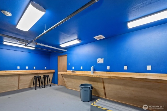 miscellaneous room with finished concrete flooring, visible vents, and bar