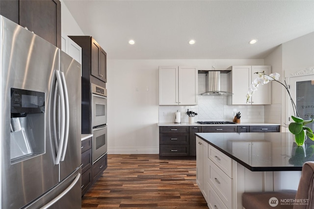 17908 NE 391st St, Amboy, WA 98601 - kitchen featuring dark wood-type flooring, wall chimney range hood, stainless steel appliances, decorative backsplash, and baseboards