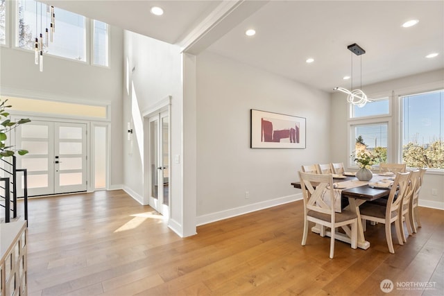 dining space featuring french doors, recessed lighting, an inviting chandelier, light wood-style flooring, and baseboards