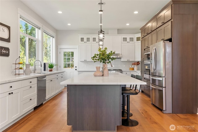 kitchen with light wood-style floors, a kitchen breakfast bar, a sink, and appliances with stainless steel finishes