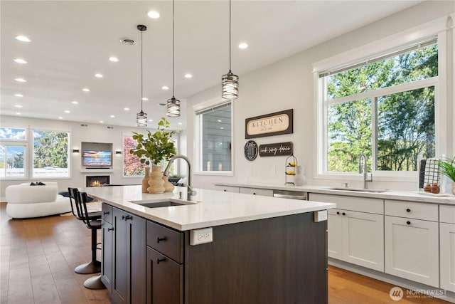 kitchen with light wood finished floors, white cabinets, recessed lighting, and a sink