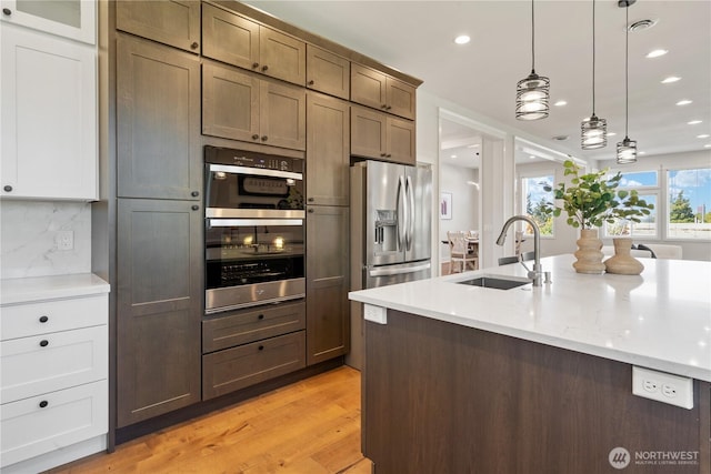 kitchen with a sink, stainless steel appliances, decorative backsplash, and recessed lighting