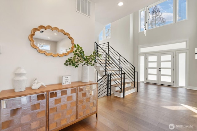 foyer entrance featuring recessed lighting, visible vents, stairs, wood finished floors, and a high ceiling