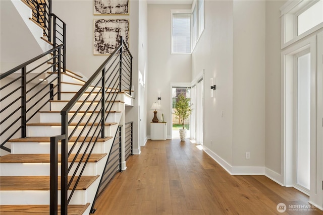 foyer with baseboards, hardwood / wood-style floors, a high ceiling, and stairway