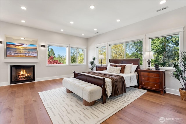 bedroom featuring recessed lighting, baseboards, hardwood / wood-style floors, and multiple windows