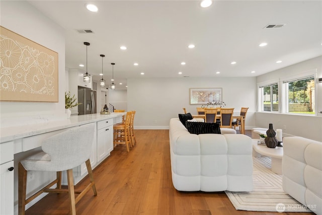 living area with light wood-type flooring, recessed lighting, and visible vents