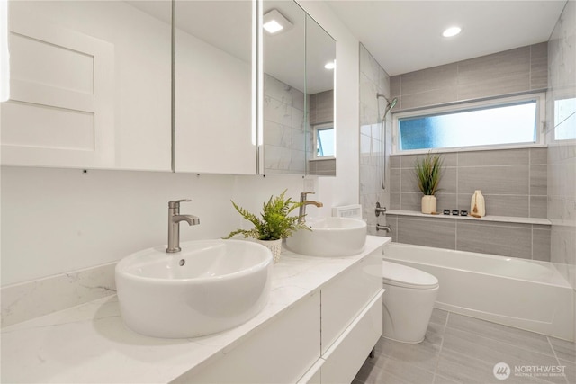 bathroom featuring a wealth of natural light, toilet, shower / bathtub combination, and a sink