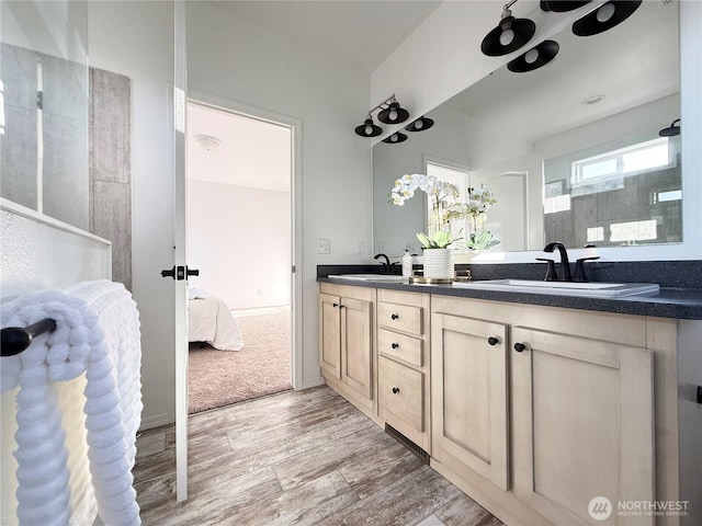 bathroom featuring wood finished floors, walk in shower, ensuite bathroom, and double vanity