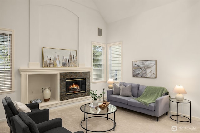 carpeted living room featuring a glass covered fireplace, plenty of natural light, baseboards, and high vaulted ceiling