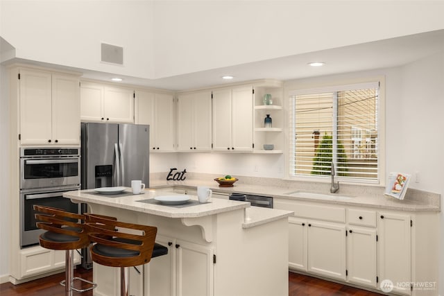 kitchen featuring a sink, appliances with stainless steel finishes, dark wood-style floors, a center island, and recessed lighting