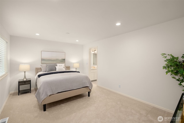 bedroom with light colored carpet, recessed lighting, baseboards, and ensuite bath
