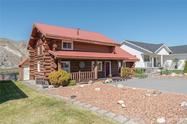 view of front of house featuring central AC unit, log siding, a mountain view, a porch, and fence