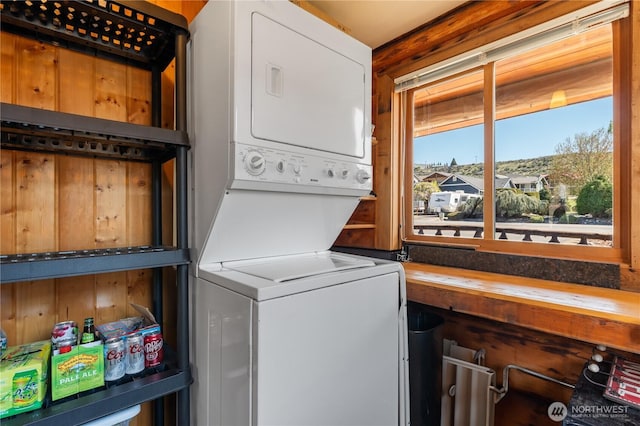 clothes washing area with stacked washer and dryer and laundry area