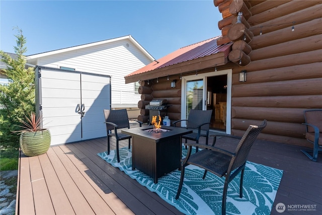 wooden terrace featuring a fire pit and a grill