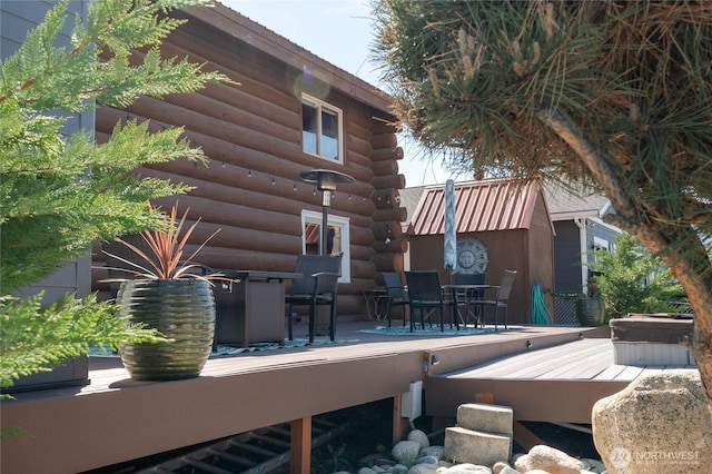 view of patio with a wooden deck, outdoor dining space, and a covered hot tub
