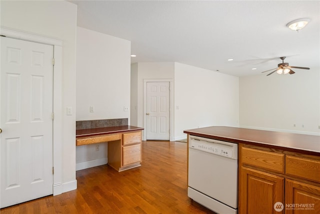 kitchen with dark wood-style flooring, dark countertops, built in study area, ceiling fan, and dishwasher