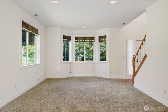 carpeted spare room featuring baseboards, stairs, visible vents, and recessed lighting