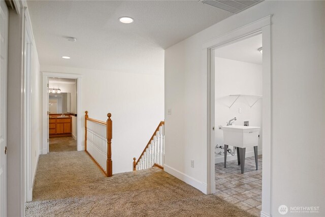 hall with recessed lighting, visible vents, an upstairs landing, baseboards, and light colored carpet