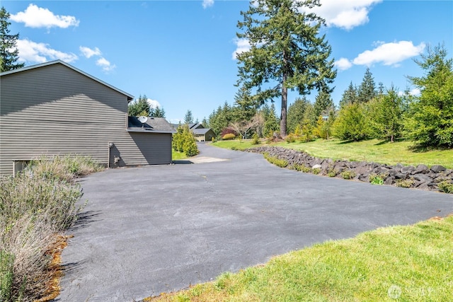 view of side of property with a lawn and aphalt driveway