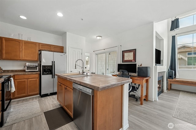 kitchen with dishwasher, fridge with ice dispenser, a sink, and light wood-style floors