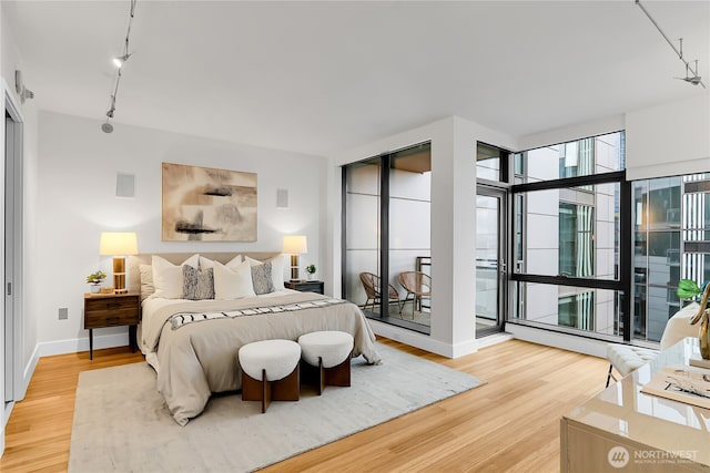 bedroom with track lighting, baseboards, and wood finished floors