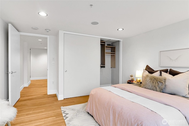 bedroom featuring a closet, light wood-style flooring, recessed lighting, and baseboards